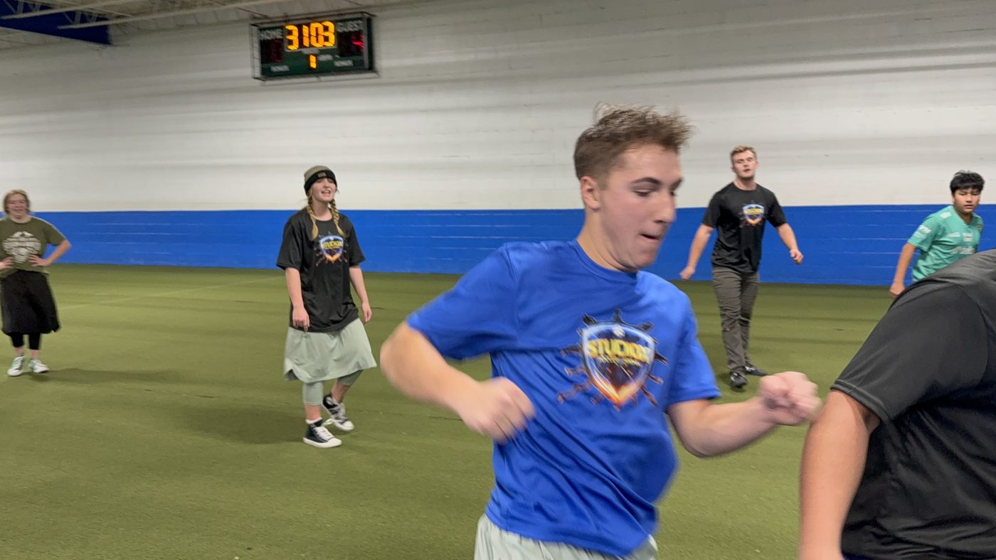 Players on the indoor turf field at StudioX Soccer Arena with scoreboard visible